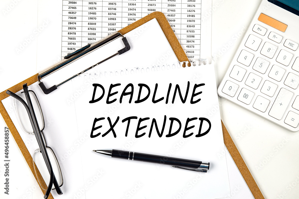 Aufkleber text deadline extended on the white paper on clipboard with chart and calculator