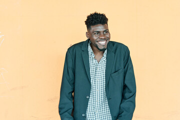 young handsome african american man laughing shyly and cheerfully, with a friendly and positive but...