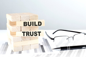 BUILD TRUST is written on wooden blocks on a chart background