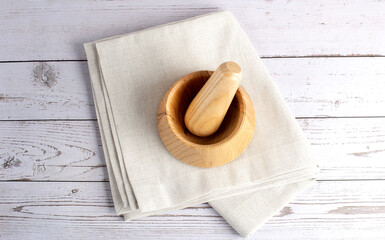 Wooden mortar and pestle with napkin on wooden table