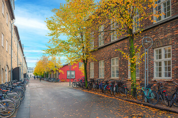 a small paved street with old wooden and brick houses and bicycles that line its edges on the island Dokøen. Copenhagen, Denmark