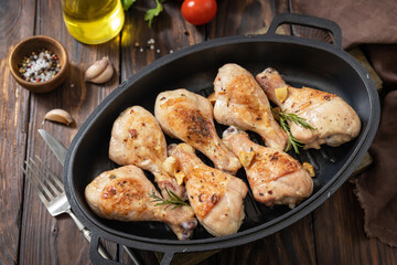Baked grilled chicken legs  with rosemary on a wooden table.