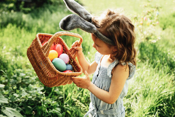 Easter egg hunt. Girl child Wearing Bunny Ears Running To Pick Up Egg In Garden. Easter tradition....