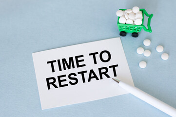text TIME TO RESTART on a white card on a blue background next to a pen and white tablets, medical concept