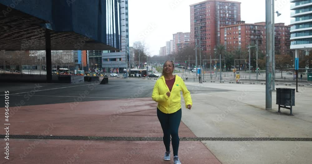 Wall mural Senior african woman running outdoor in the city during rainy day