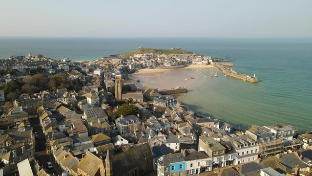 Cinematic drone and aerial footage over St. Ives. Beach in North Cornwall. Green seas and blue skies and surfers enjoying the waves