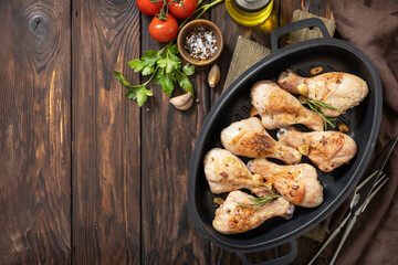Baked grilled chicken legs  with rosemary on a wooden table. Top view flat lay. Copy space.