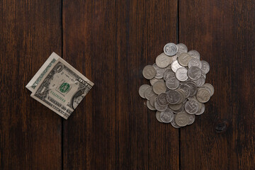 one dollar bill equal to a pile of ruble coins on a dark wooden background