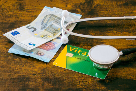 carte vitale de France et un stéthoscope et des billets en euros  sur une table en bois 