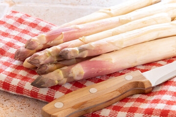raw white asparagus on a table with a knife