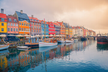 The most popular place of the city the Nyhavn canal with a pier with many boats, yachts and ships, located near the old beautiful colorful houses. Copenhagen, Denmark