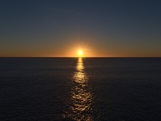 Stunning sunset with bright sun on the horizon above the Atlantic Ocean viewed from Playa de Amadores in Puerto Rico, southern Gran Canaria, Spain.