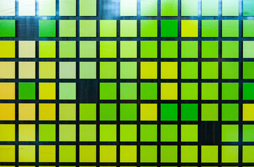 Mosaic of small green-yellow squares on glass, close-up. Matrix style digital squares.
