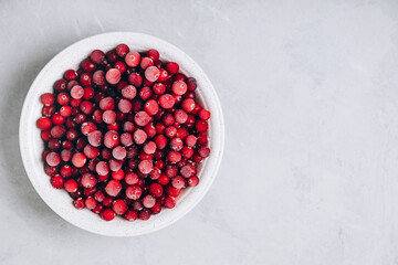 Cranberries. Frozen cranberry in bowl on gray stone background