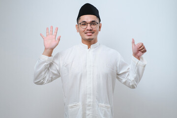 Fototapeta premium Asian muslim man wearing casual clothes showing and pointing up with fingers number six while smiling confident and happy