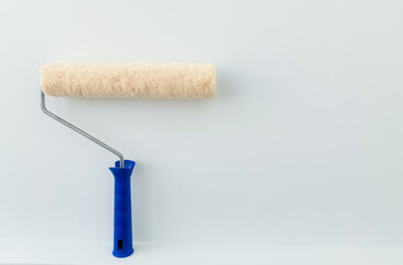 girl paints the wall with white paint. female hand with wall paint roller close up with copy space