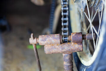 The mechanic is cutting the motorcycle chain and fixing the motorcycle.