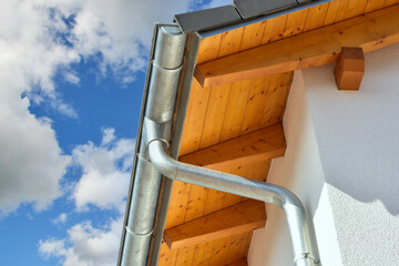 Dachrinne mit Wasserfangkasten und Regenfallrohr aus Zinkblech an einem Neubauhaus