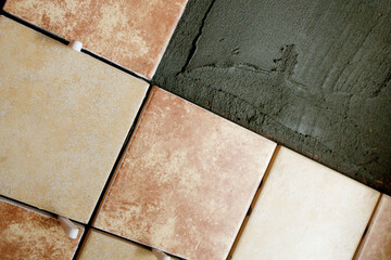 A section of freshly laid brown and cream tiles on the wall with plastic gaskets. Repair work