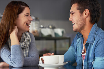 He always makes her smile. A loving young couple at a coffee shop together.