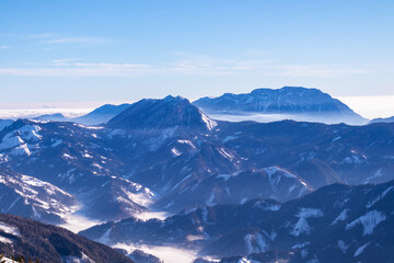 Obraz premium Active woman snow shoe hiking on a trail with scenic view on snow capped mountain peaks of Karawanks in Carinthia, Austria. Ski tour. Julian Alps. Sunny winter day. Freedom. Winter wonderland,Hochobir