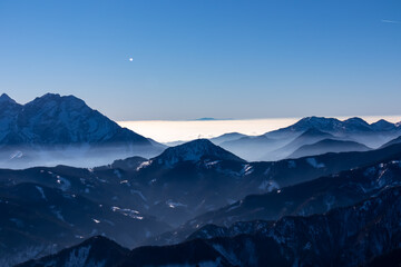 Panoramic view on snow capped mountain peaks of Karawanks in Carinthia, Austria. Julian Alps. Winter wonderland in the Austrian Alps, Europe. Ski tour, snow shoe hiking. Hochobir. Blue misty hills.