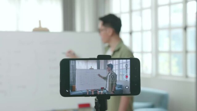Close Up Of Smartphone Camera Recording Asian Male Teacher With Glasses Teaching English At Home
