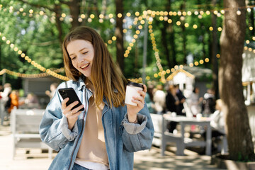 A woman walks in the park holding a cup of coffee in her hand