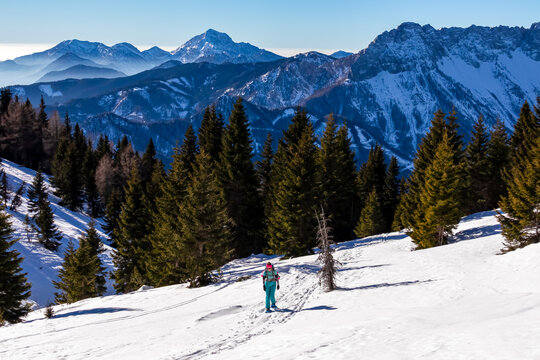 Active woman snow shoe hiking on a trail with scenic view on snow capped mountain peaks of Karawanks in Carinthia, Austria. Ski tour. Julian Alps. Sunny winter day. Freedom. Winter wonderland,Hochobir