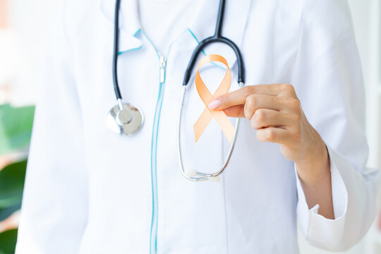 Close up of a doctor holding and showing orange awareness ribbon in her hands