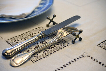 Antique cutlery made of blackened silver, a knife and fork lie on a decorative holder for cutlery...