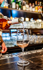 bartender pouring rose wine into a glass in cafe or bar