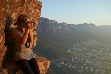 Snapshots from the summit. Shot of a woman taking a picture with her camera on top of a mountain.