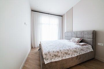 interior of a white room with a large window and a clean bed