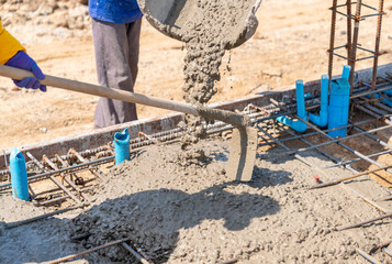 Worker using hoe to spread concrete.