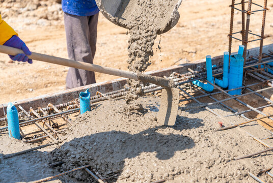 Worker Using Hoe To Spread Concrete.