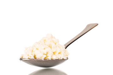Fragrant tasty cottage cheese with a metal spoon, macro, isolated on a white background.