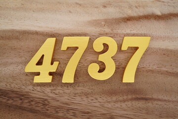 Golden Arabic numerals on a real brown and white wooden floor number 4737