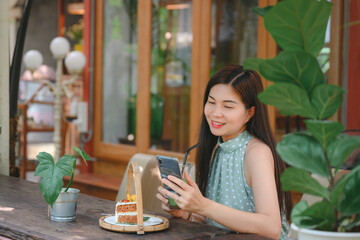 Smiling beautiful Asian woman eating green tea and snacks in a cafe to relax on a leisurely day....
