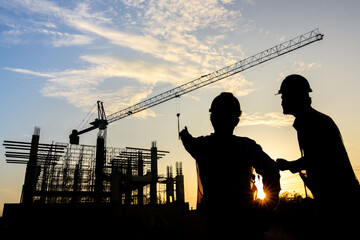 Construction engineer team silhouette talking to managers and construction workers at a...