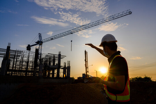professional engineer work on a construction site Project work plan for designing houses and industrial buildings construction site at sunset in the evening