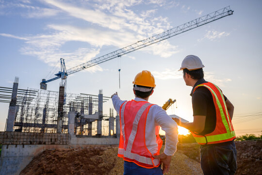 A team of construction engineers talks to managers and construction workers at the construction site. Quality inspection, work plan, home and industrial building design project