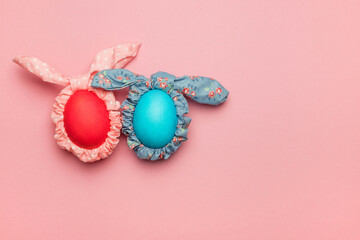 Easter eggs with pink and blue bunny ears and on a pink background. Minimal Easter concept. Postcard. Flat lay, top view.