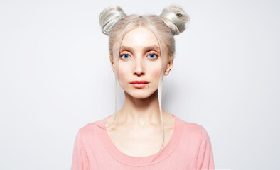 Studio portrait of pretty girl with blonde hair buns, on white background.