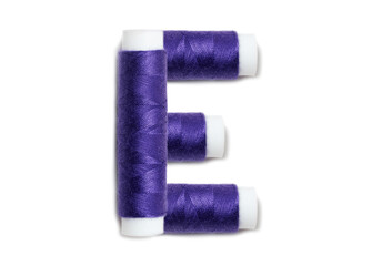 Letter of E from thread spools, isolated on white background. Alphabet concept.
