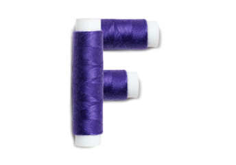 Letter of F from thread spools, isolated on white background. Alphabet concept.