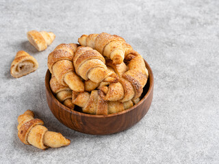 Crescent rolls cookies in brown wooden bowl. Cinnamon and sugar biscuits. Closeup view. Light grey background. Tasty homemade dessert or snack. Copy space. 