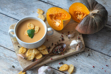 Ripe pumpkin, pumpkin soup puree on a wooden table.