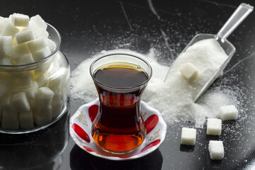 Traditional and Classic Turkish Tea with sugar cubes and granulated sugar on a black marble table