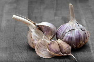 Czosnek (polski czosnek ma osnówkę lekko fioletową lub jasnoróżową) na desce. Garlic (Polish garlic has a warp that is slightly purple or light pink) on a board. - obrazy, fototapety, plakaty